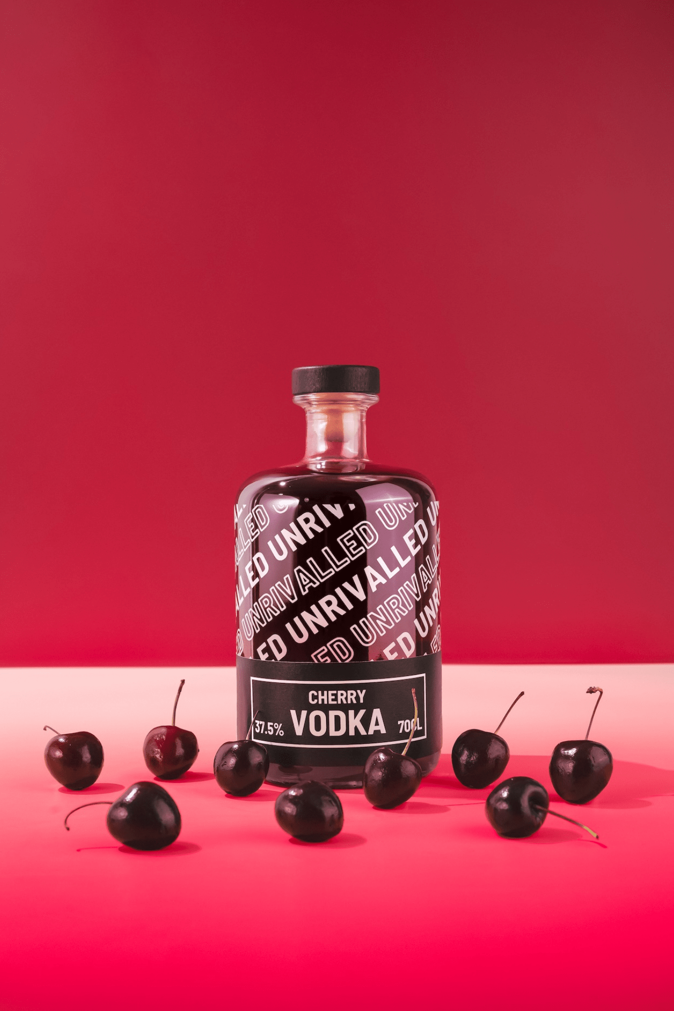 Bottle of Unrivalled Cherry Vodka with cherries on a red background