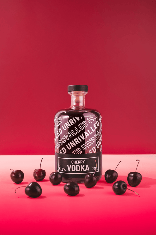 Bottle of Unrivalled Cherry Vodka with cherries on a red background