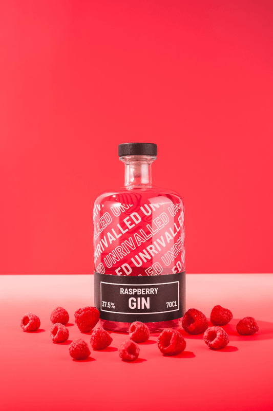 Bottle of raspberry gin with raspberries on a red background